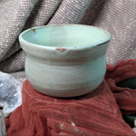 Mint green matcha tea bowl on a textured fabric background