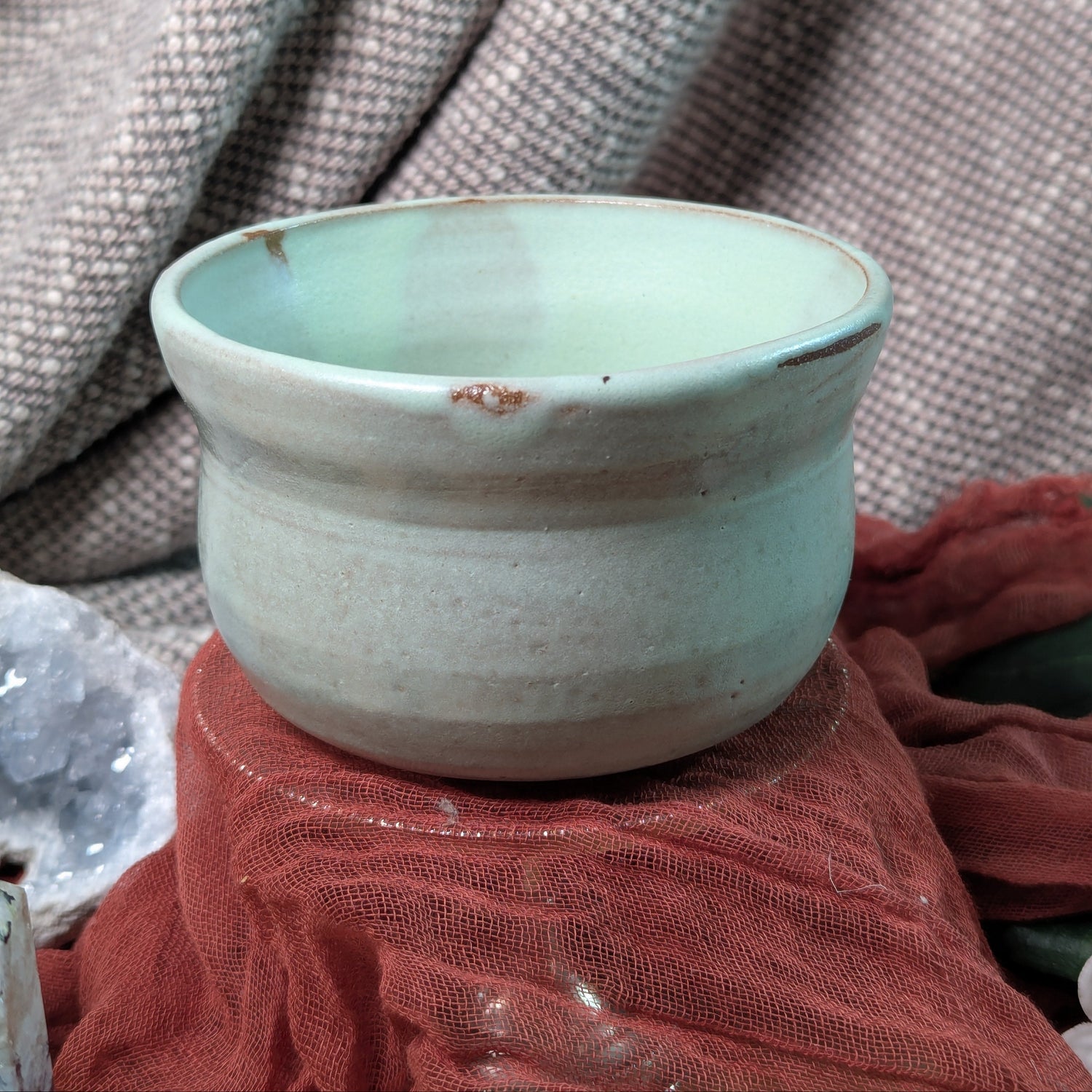 Mint green matcha tea bowl on a textured fabric background