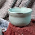 Mint green matcha tea bowl on a textured surface with a neutral background