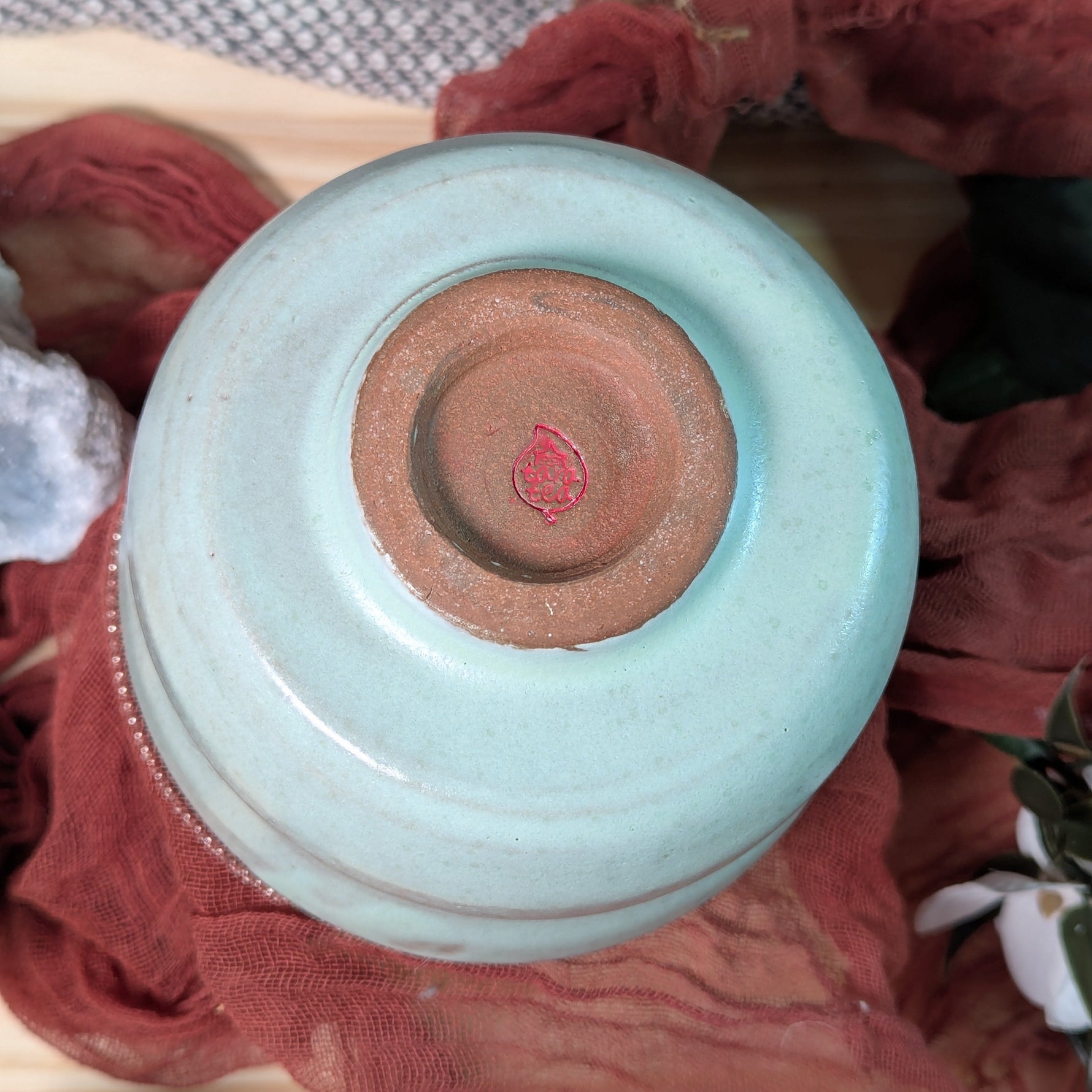 Mint green matcha tea bowl with a red tara tea potter's stamp on the bottom of the bowl