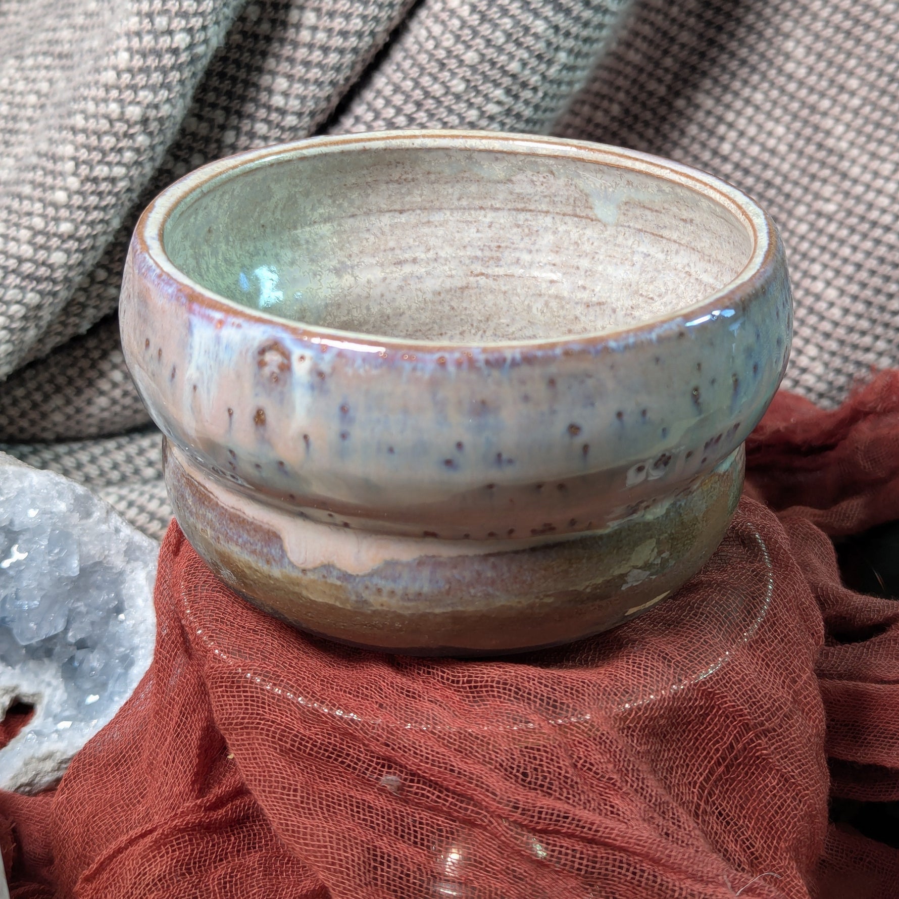 Ceramic bowl with pearl glaze on a textured fabric background