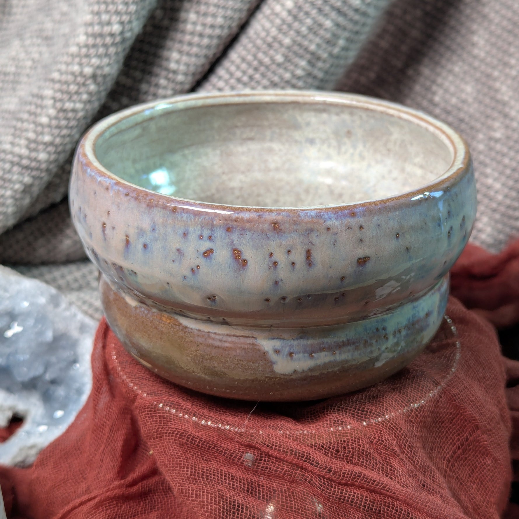 Ceramic bowl with a pearl glaze on a textured surface