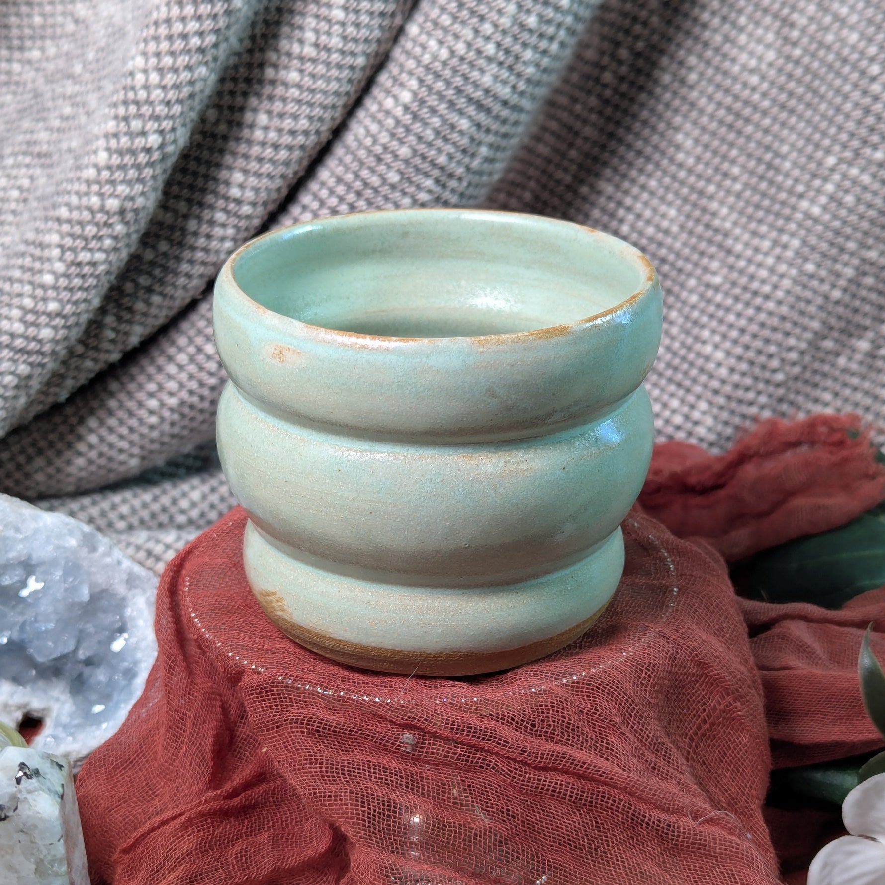 mint green ceramic cup on a textured surface with a blurred background