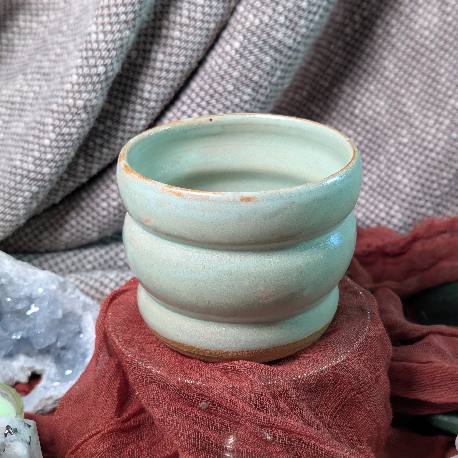 mint green ceramic cup on a textured surface with a blurred background