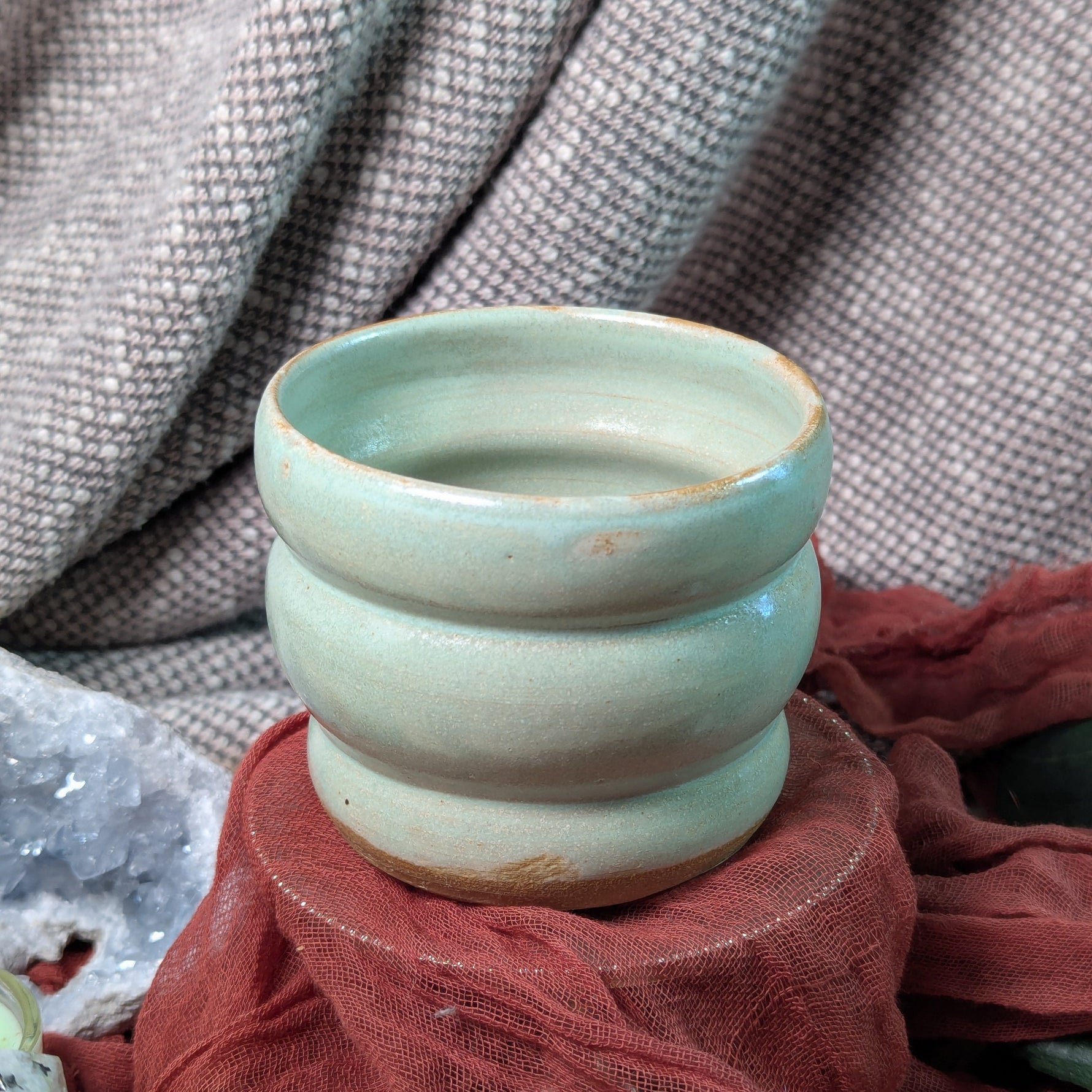 mint green ceramic cup on a textured surface with a blurred background