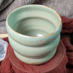 mint green ceramic cup on a textured surface