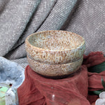 Speckled ceramic bowls on a textured surface with a fabric background