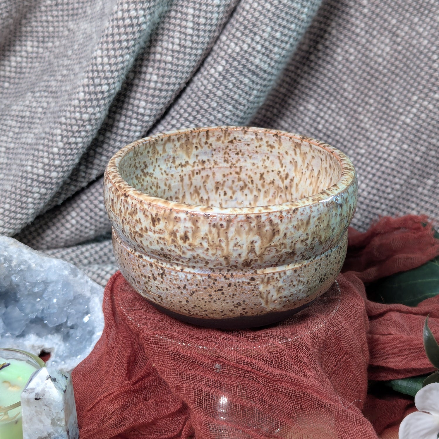 Speckled ceramic bowls on a textured surface with a fabric background