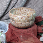 Speckled ceramic bowl on a textured surface with a blurred background