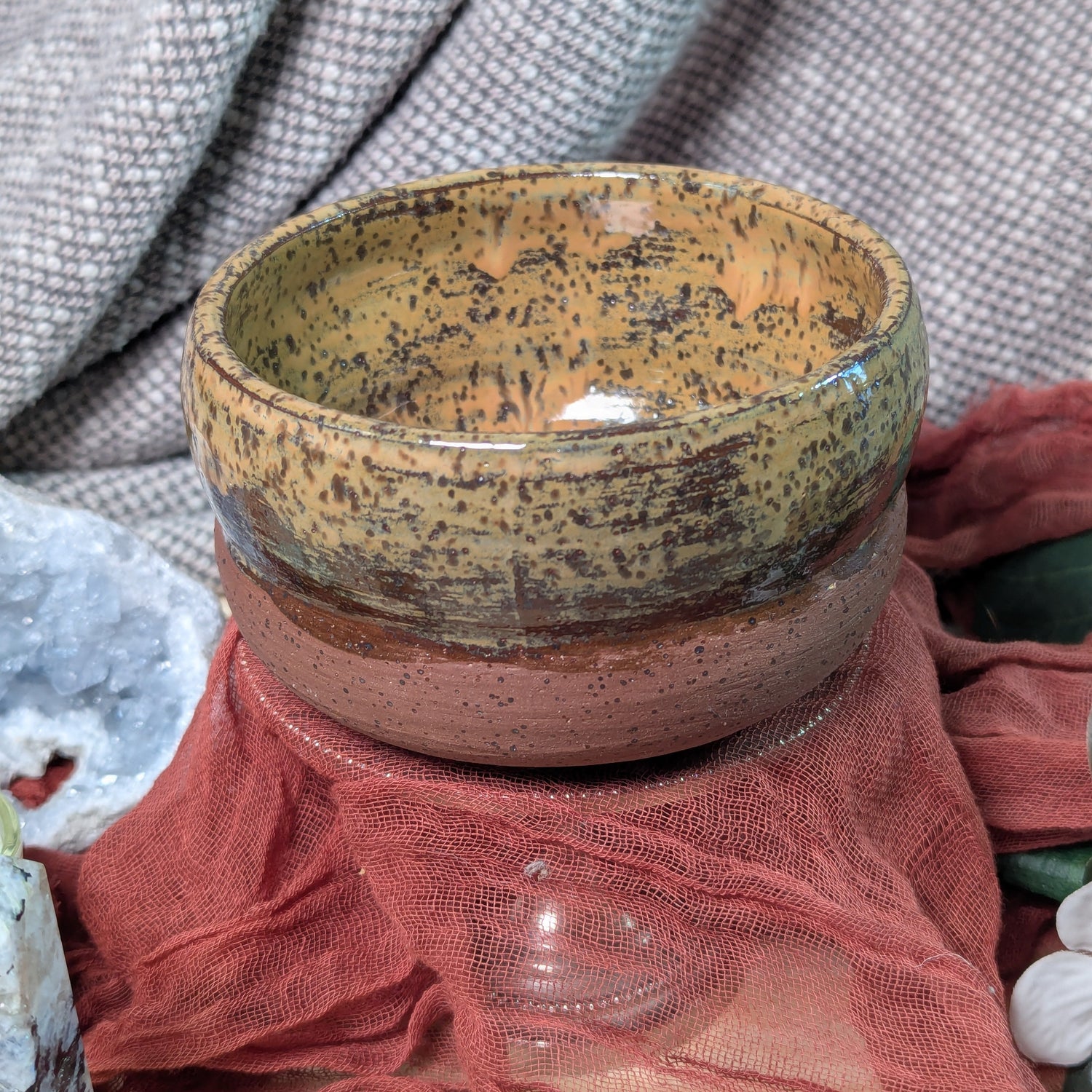 Ceramic bowl with speckled glaze on a textured fabric background