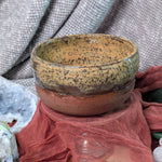 Ceramic bowl with speckled pattern on a textured surface