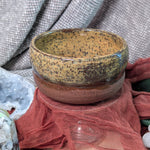 Ceramic bowl with speckled pattern on a textured surface